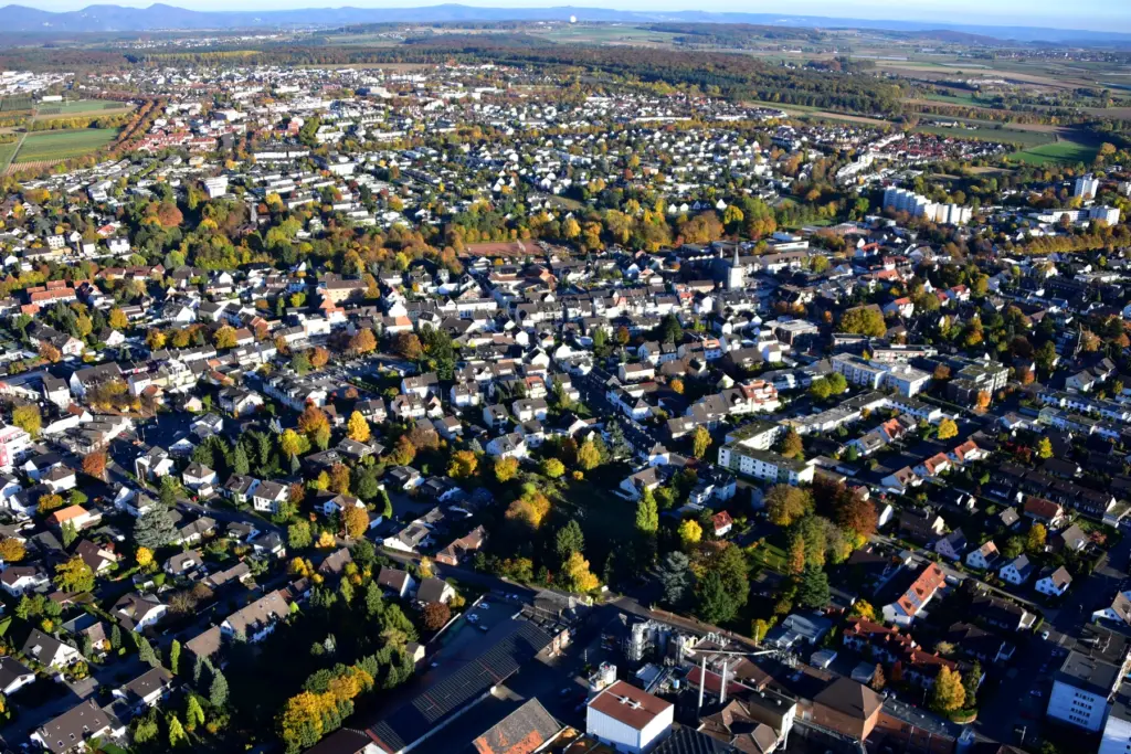 Luftbild von Meckenheim mit herbstlich gefärbten Bäumen, Wohngebieten und dem Siebengebirge am Horizont