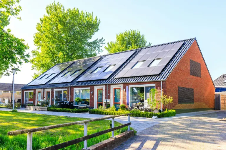 Moderne Klinker-Reihenhäuser mit Solaranlage auf dem Dach und gepflegten Vorgärten bei Sonnenschein